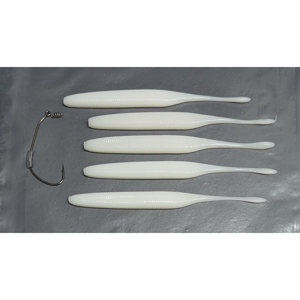 Five white 6-inch Cornish Stick bass lures beside the included 6/0 3g weighted twist-lock hook.