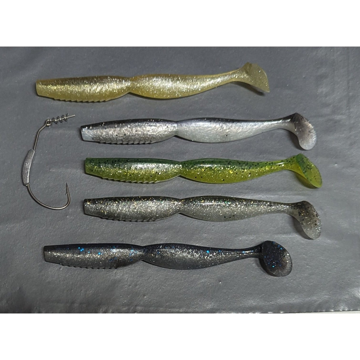 Five natural-mix Spindle paddletail bass lures beside the included 3/0 4g weighted twist-lock hook.